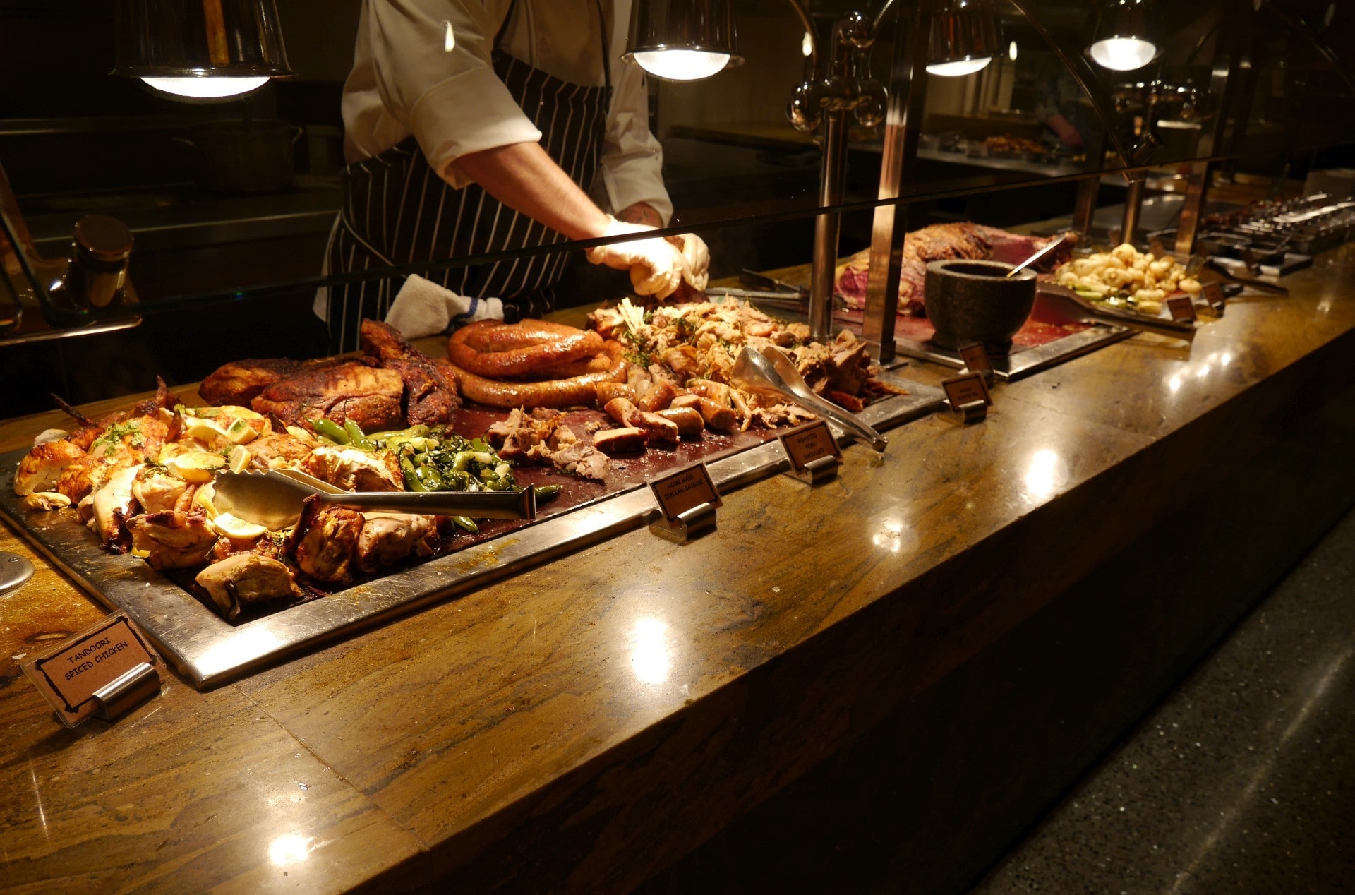 Exquisite culinary display at the Bacchanal Buffet in Caesars Palace, featuring a selection of entrees, from Tandoori spiced chicken to homemade Italian sausages, complemented by an elegant ambiance.